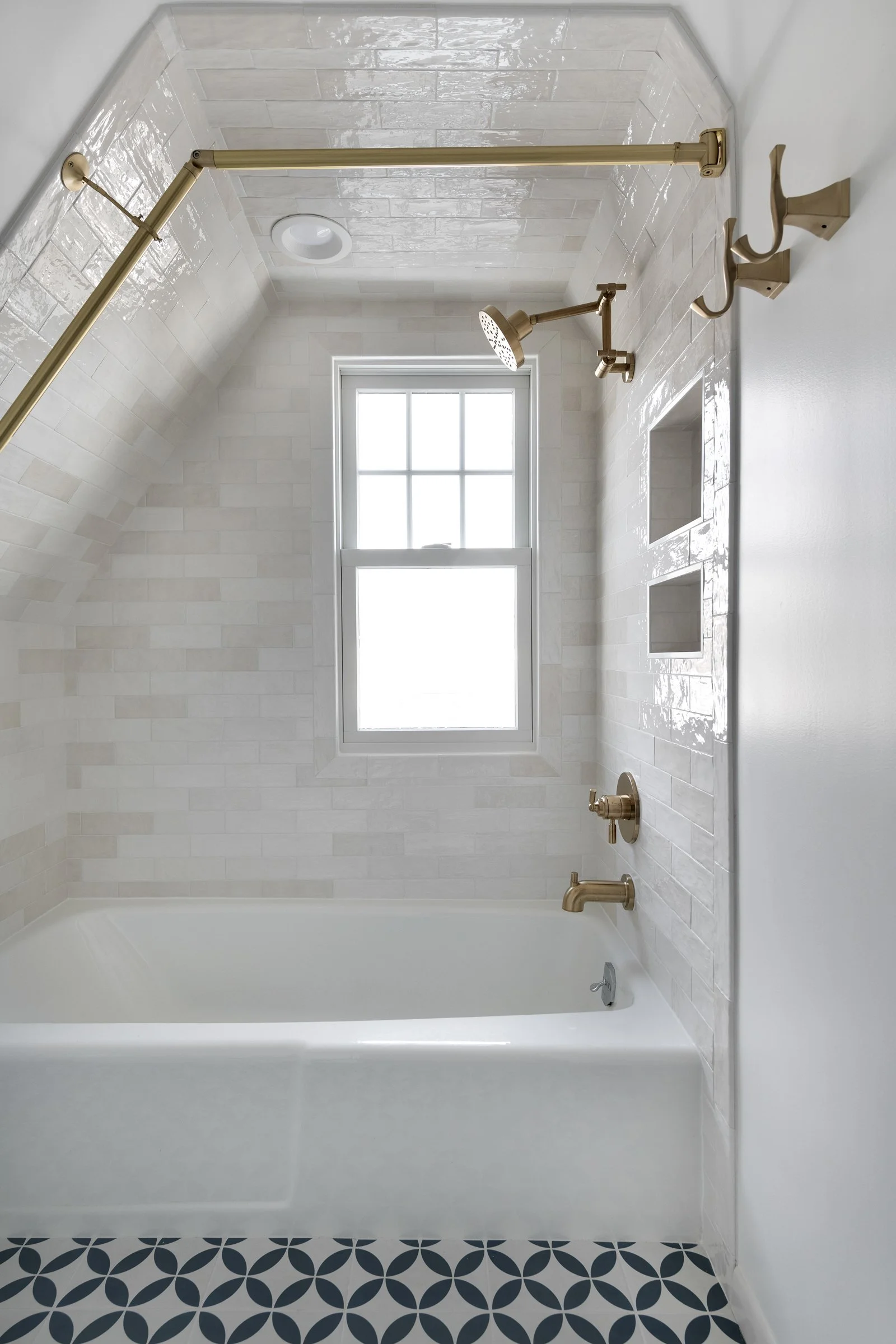 textured classic subway tile angled lshower with modern brass plumbing fixtures and a cast iron tub. the shower has storage niches and an angled shower curtain rod.