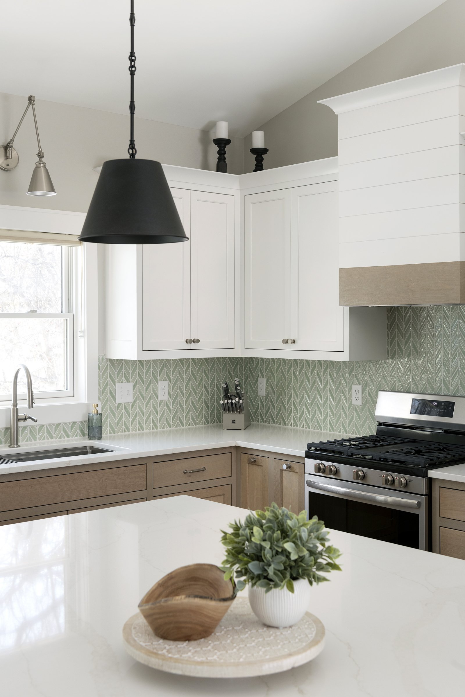 White oak and painted white inset shaker style kitchen cabinets with a light green chevron tile backsplash.