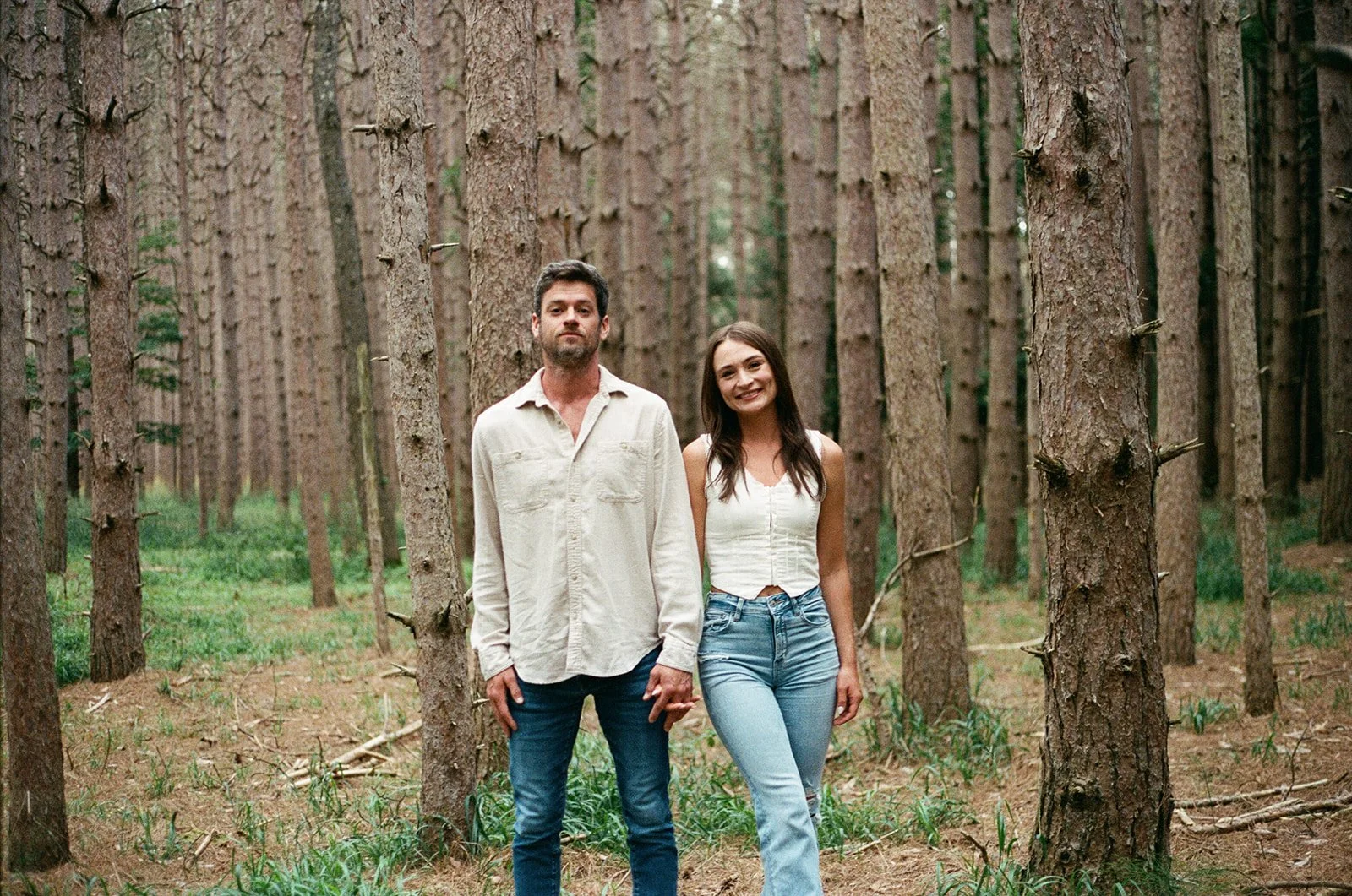A man and woman holding hands in a forest