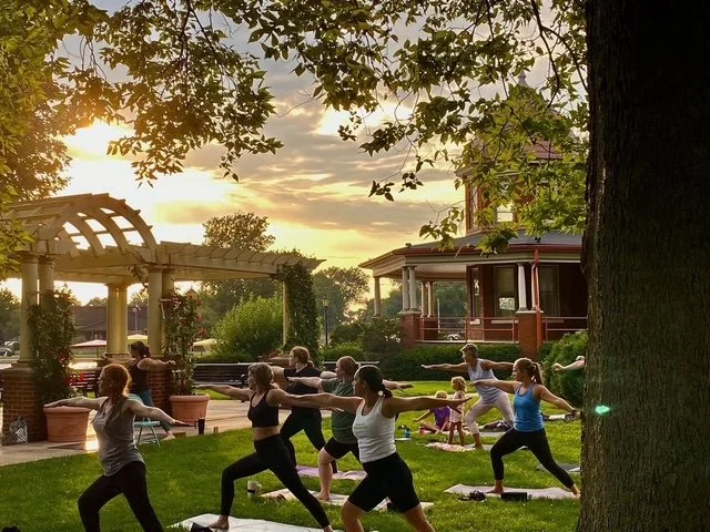 Group of women practicing yoga in a studio, doing lunges with arms extended.