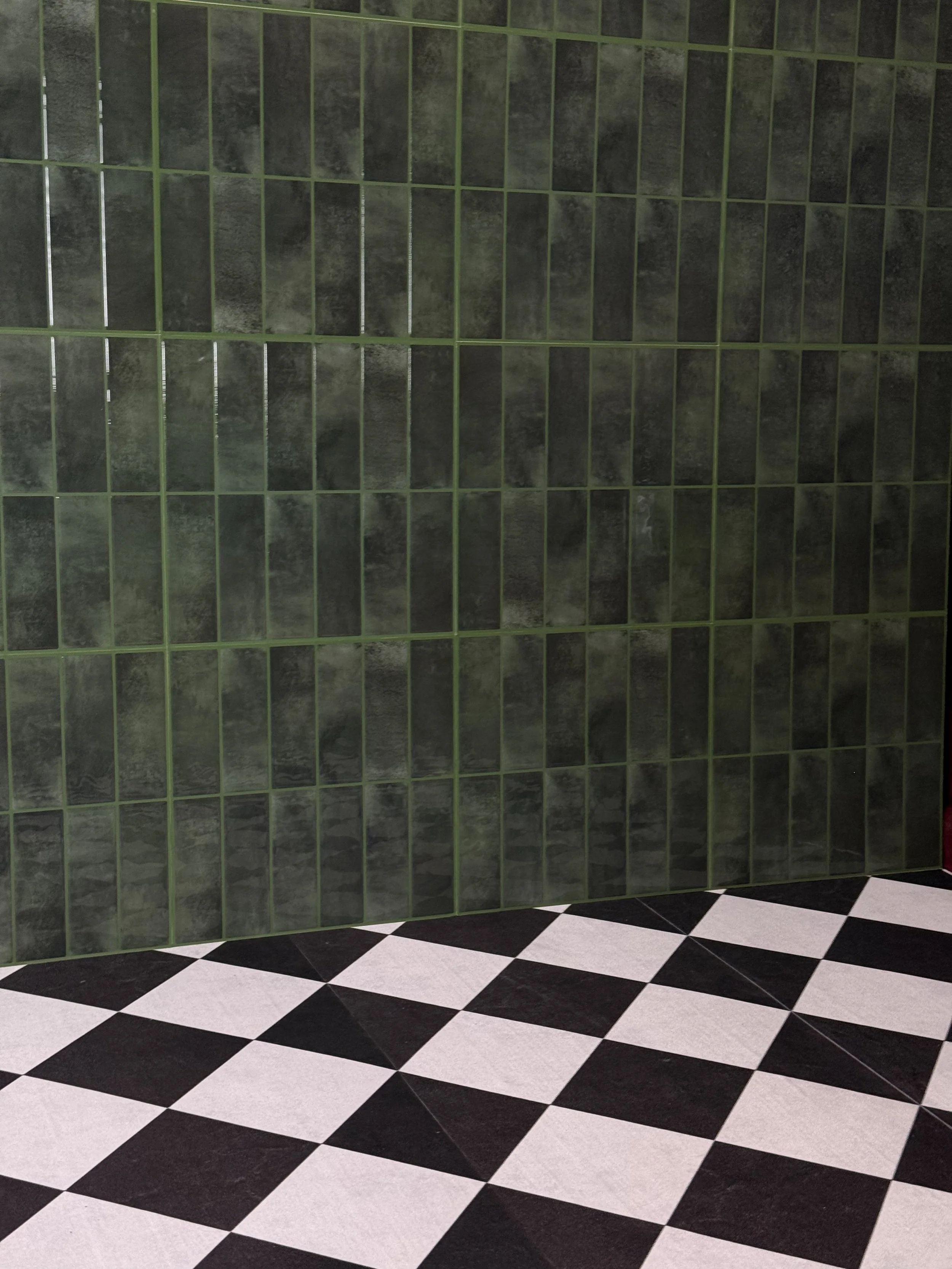 Black and white checkered tile floor with a green tiled wall in the background.