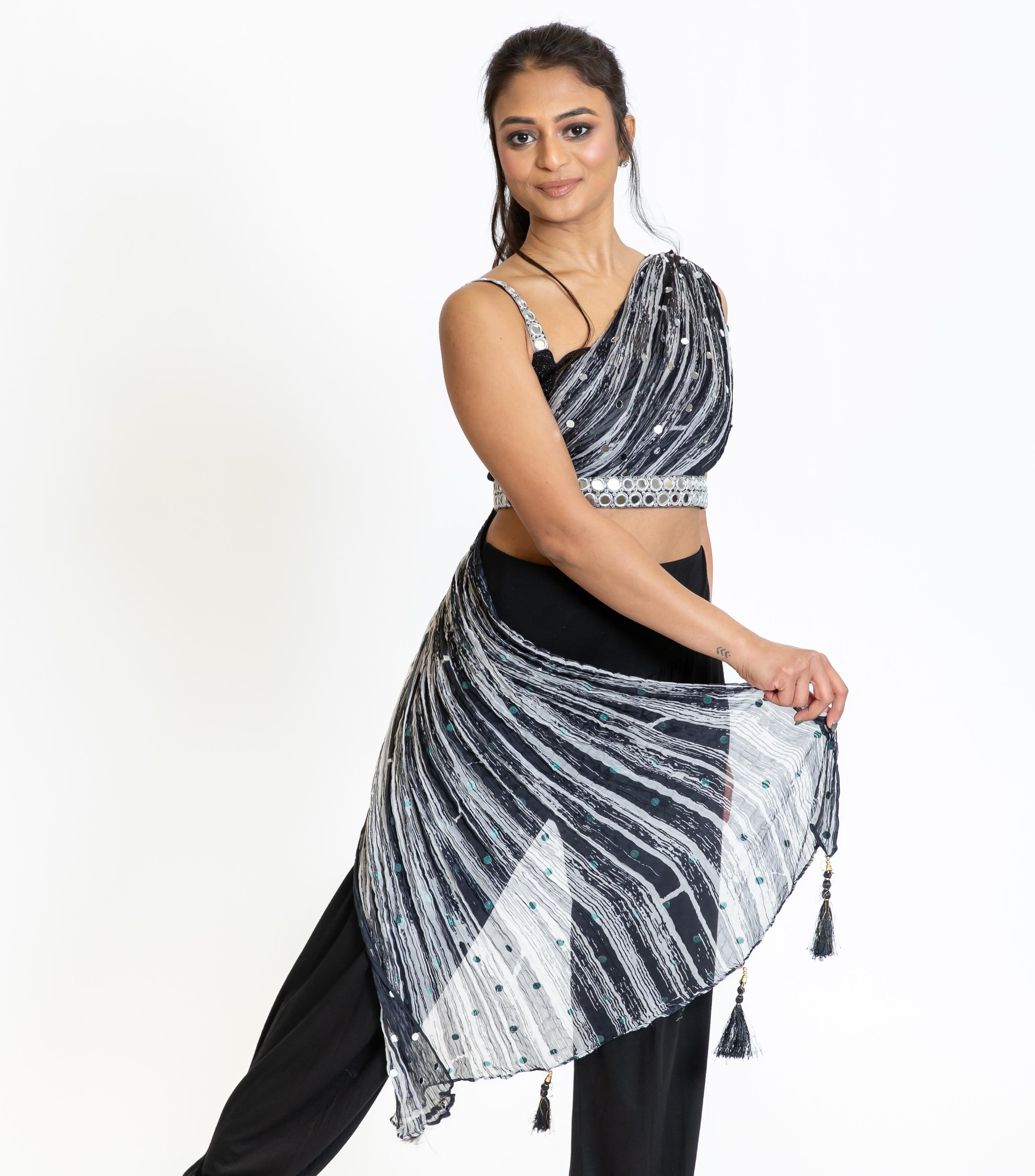 Soft movement, strong presence ✨🖤
The Mohini Top is made to mesmerize &mdash; crafted in ombr&eacute; pleated fabric with hand-done mirror work and a dramatic one-shoulder trail finished with tassels that flow beautifully with every step and spin. E