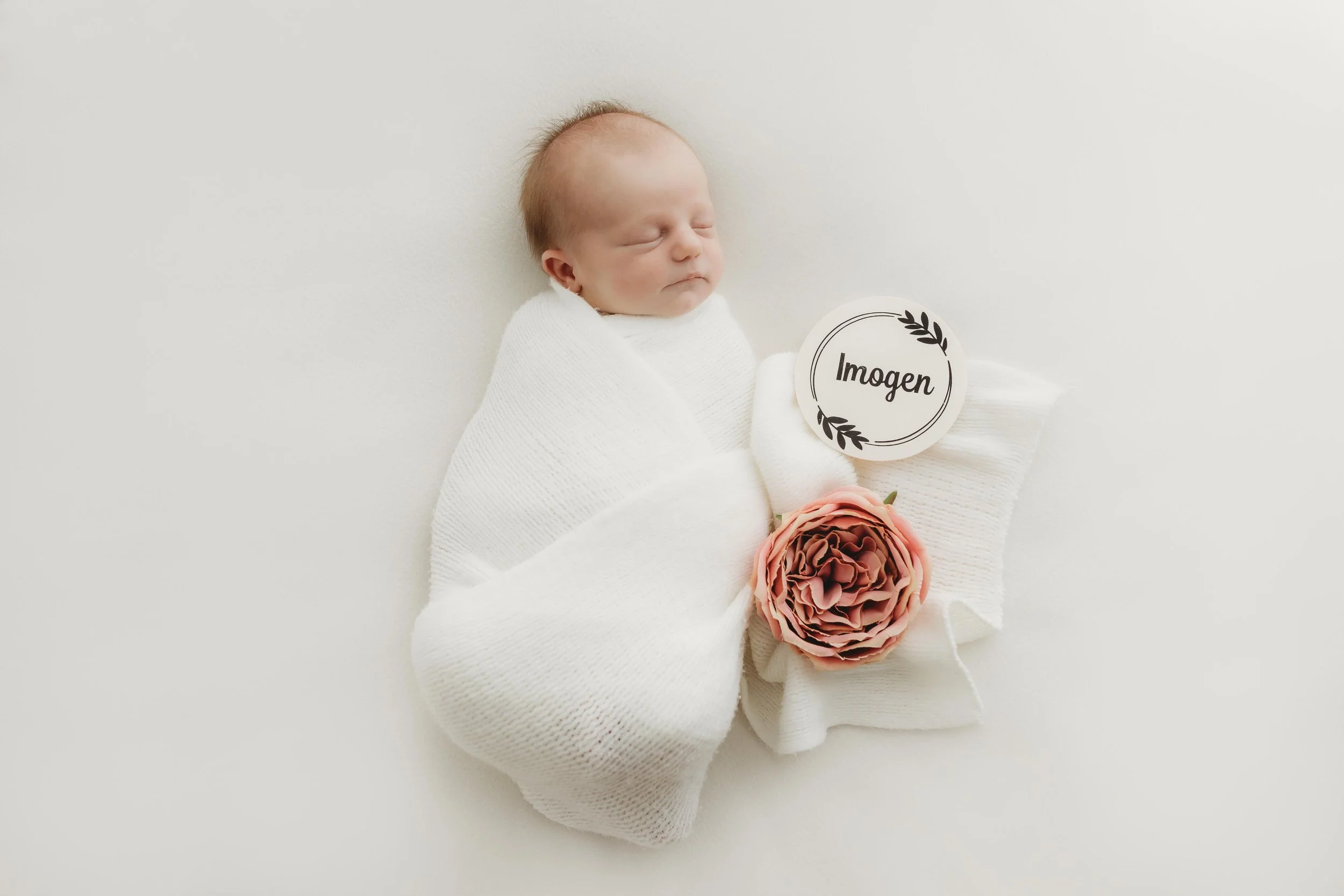 Newborn baby photographer castle hill baulkham hills northmead parramatta affordable baby lying down on a white background covered with a soft wrap and a name plaque