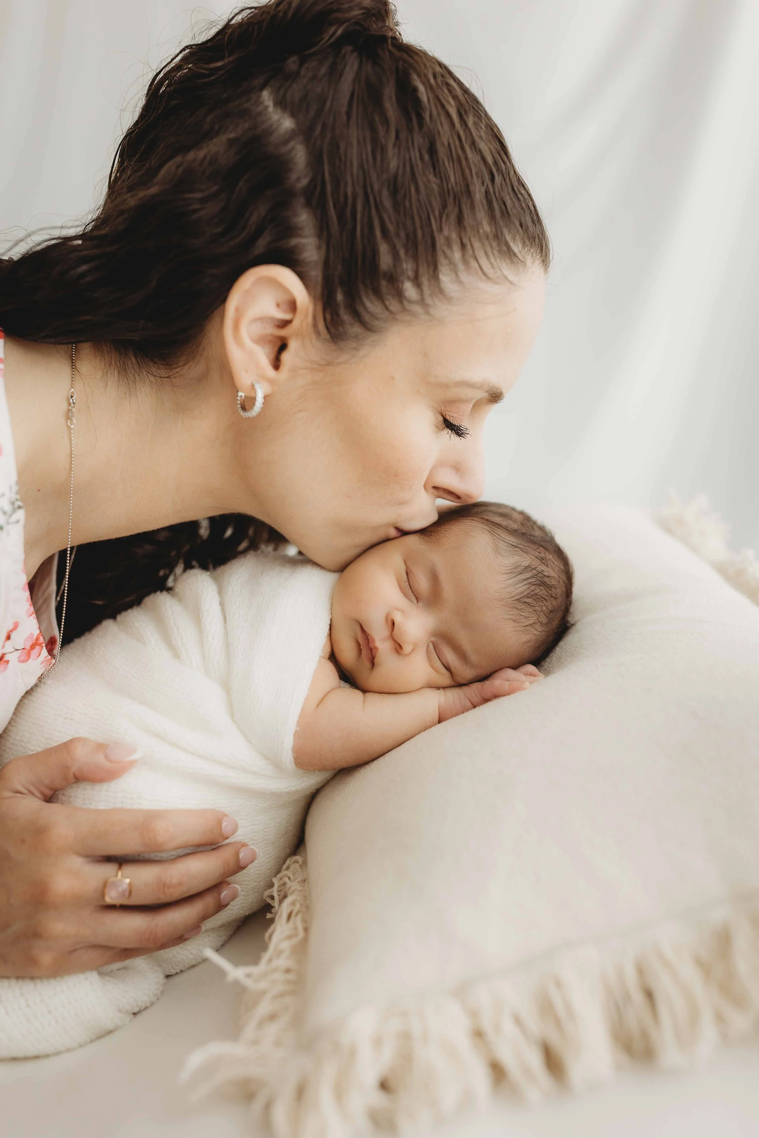 Mother kissing her beautiful baby newborn with love