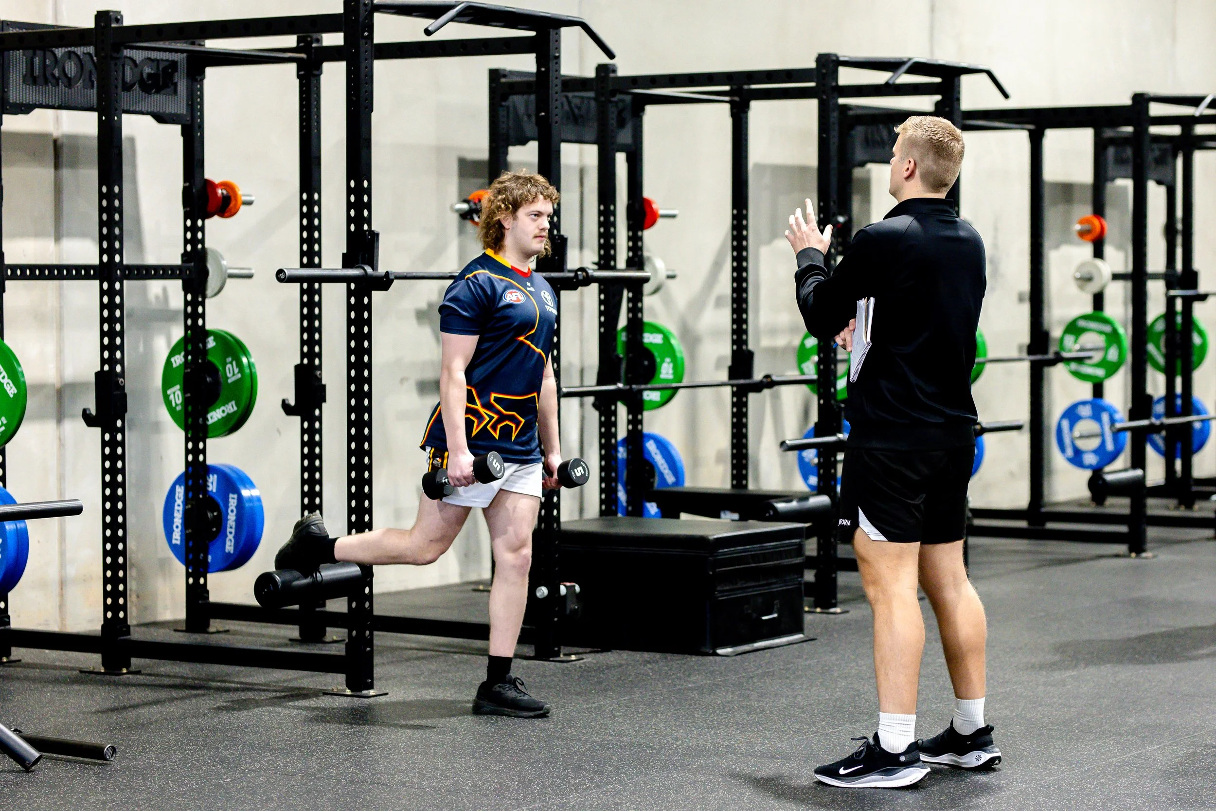 physiotherapist demonstrating split squat with injured patient