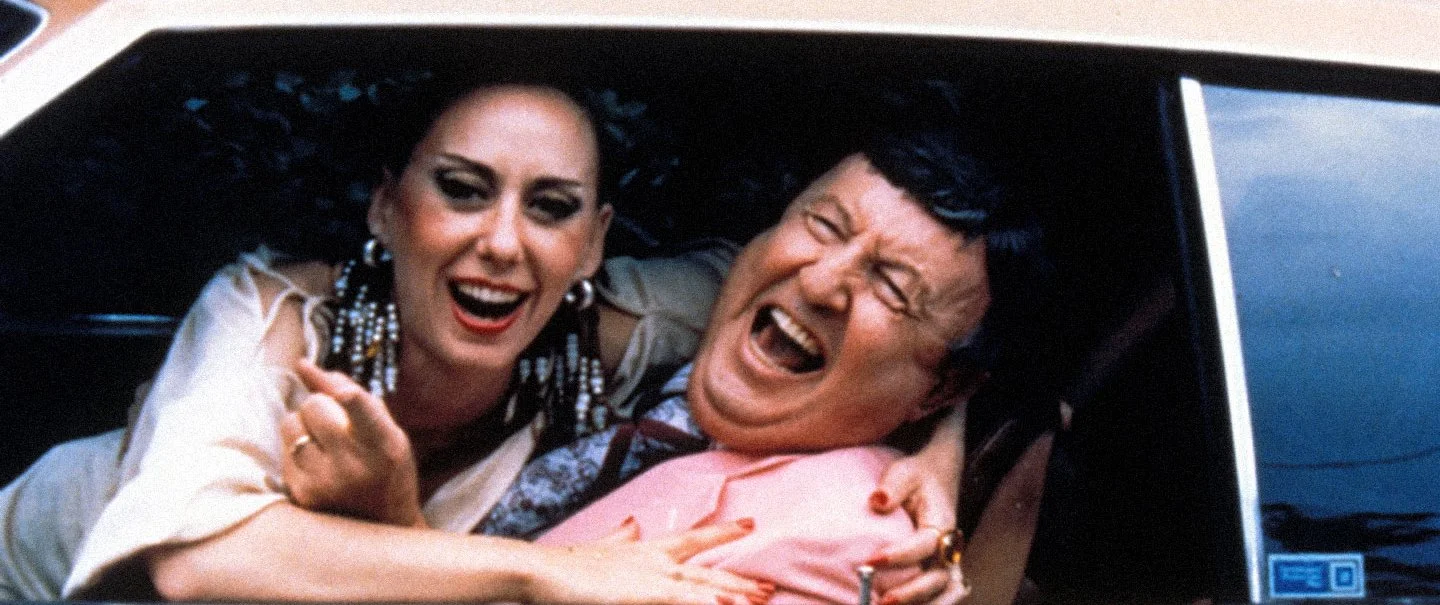 a man and a woman jeering out of a car window