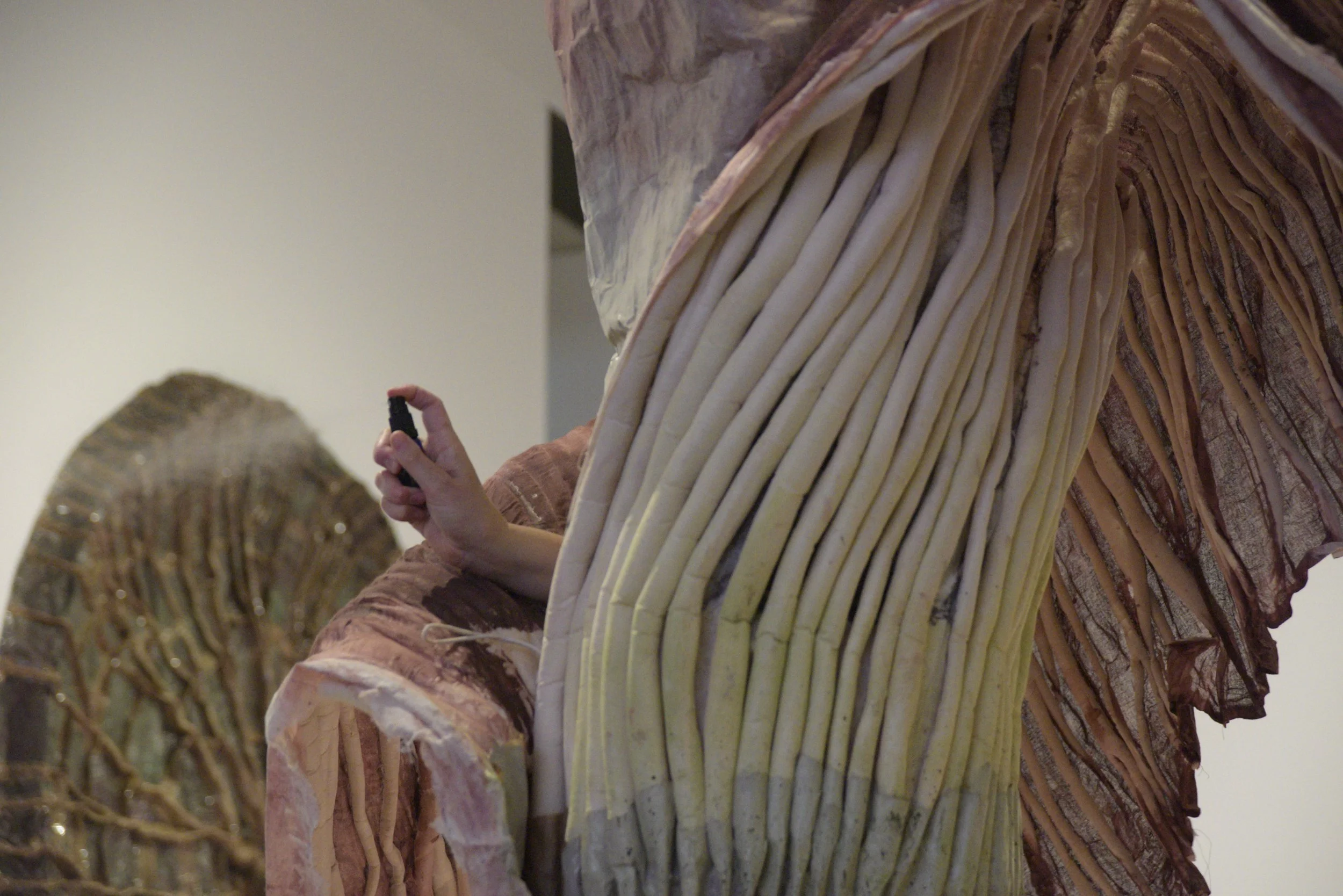 A giant corpse flower costume with a hand peeking out spraying a scent bottle