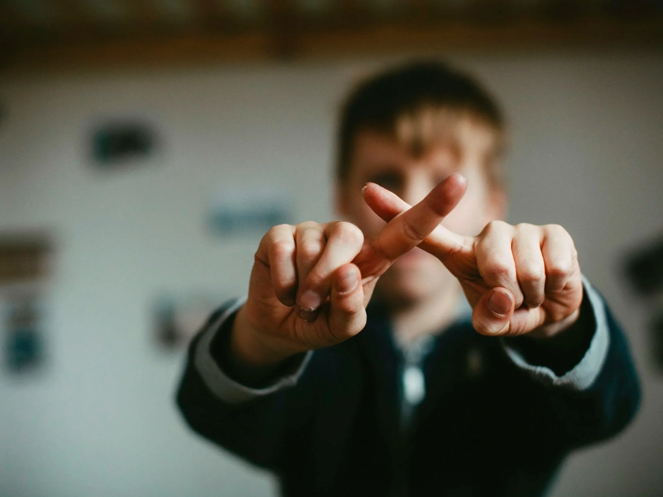 A person crossing their fingers to form an 'X' shape, symbolizing the strict boundary of going no contact with a narcissist