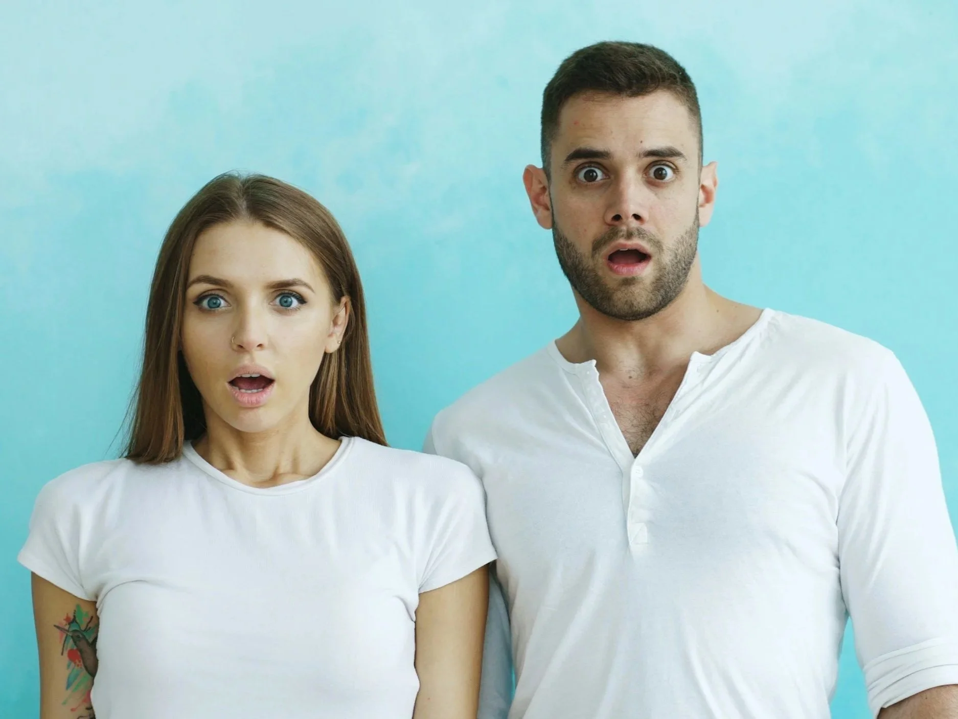 A man and a woman looking wide-eyed and shocked, capturing the sudden realization of toxic relationship patterns