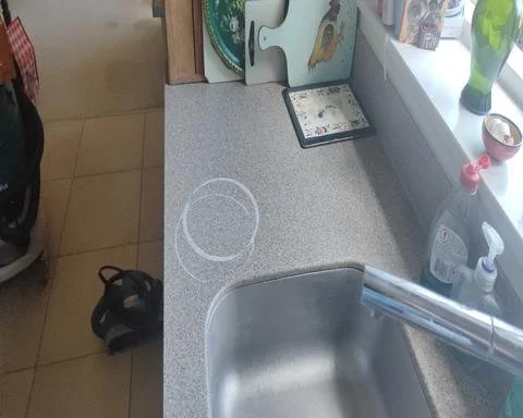 Pan burn on speckled grey solid surface kitchen worktop with damage marked out for repair in Guildford.