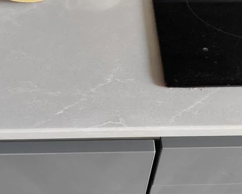 Seamlessly repaired and polished quartz worktop edge next to an induction hob in Guildford.