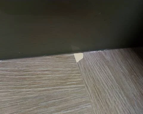 A large chip damage on a light oak laminate worktop joint exposing the core material before repair in Guildford.