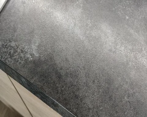The same dark textured laminate worktop with the burn damage fully rebuilt and pattern-matched in Guildford.