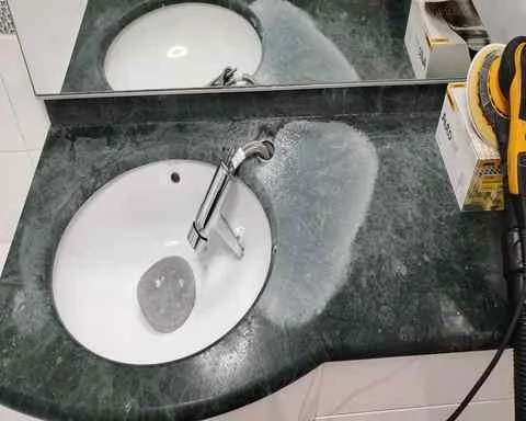 A green stone worktop that is worn and has bad water damage
