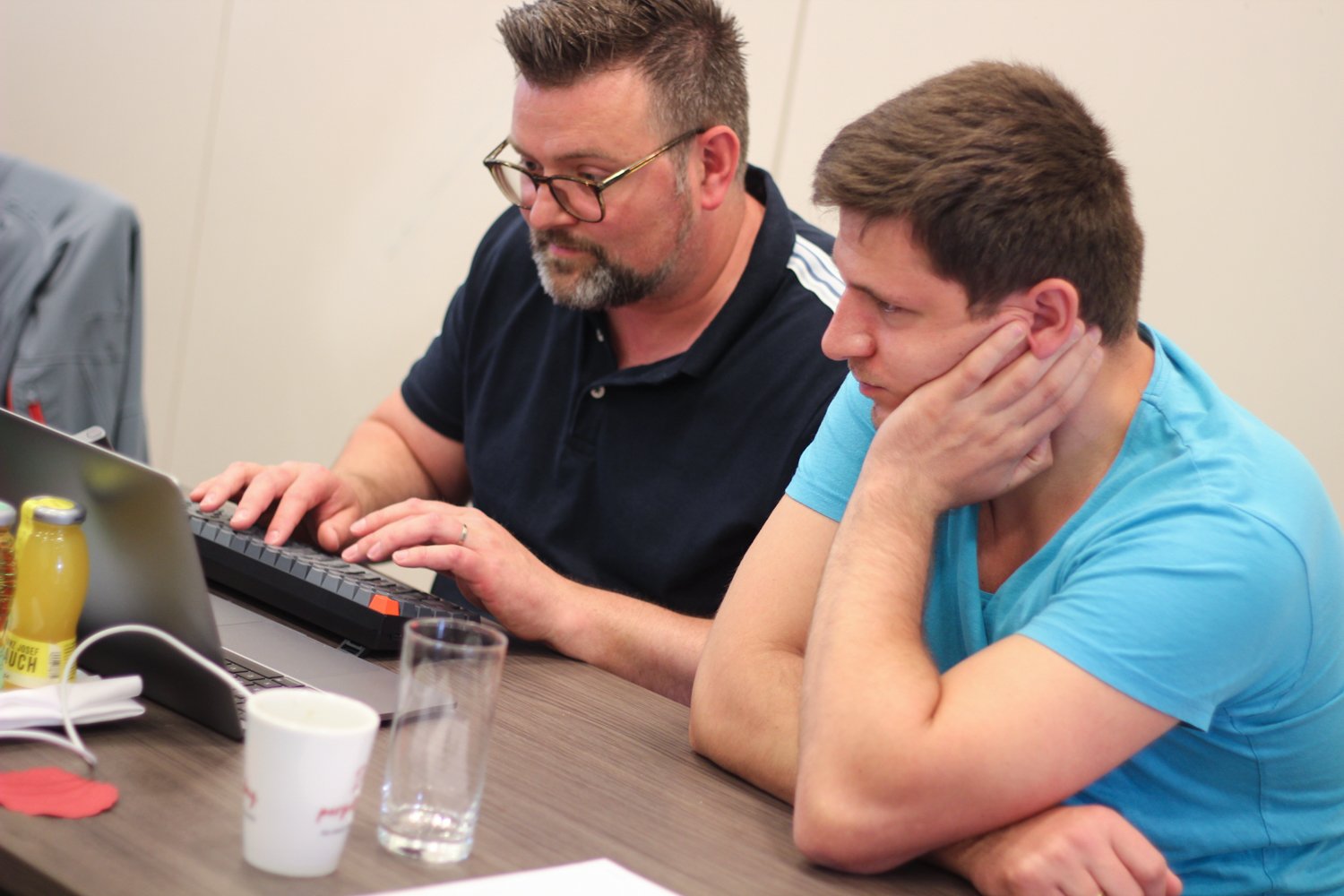 Timon and Krystian sitting next to each other in front of a laptop at a desk during a hackathon