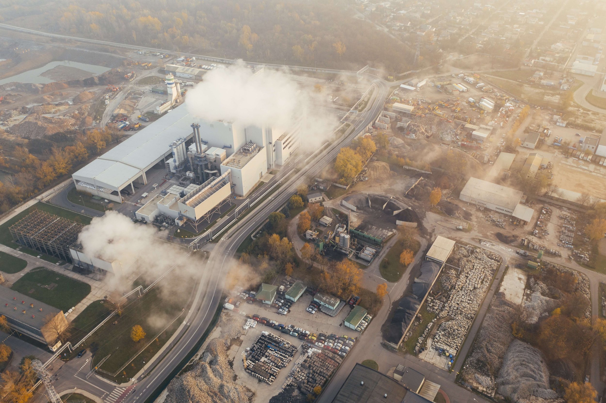 A birdeye view of a factory and its surroundings, with a cloud of fumes above it