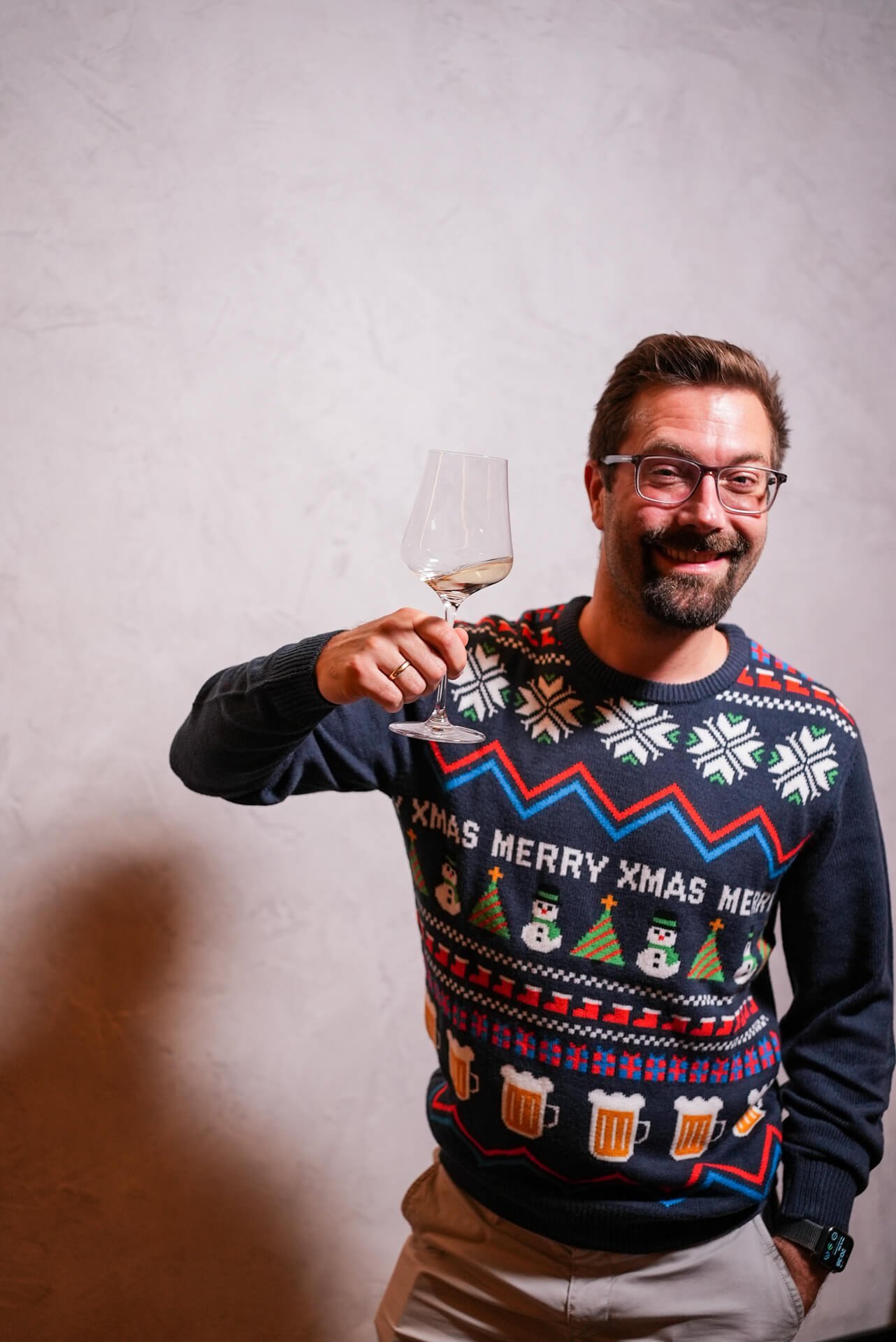 Trustbit CTO Seb wearing a Christmas sweater and holding up a glass of wine to the camera, smiling