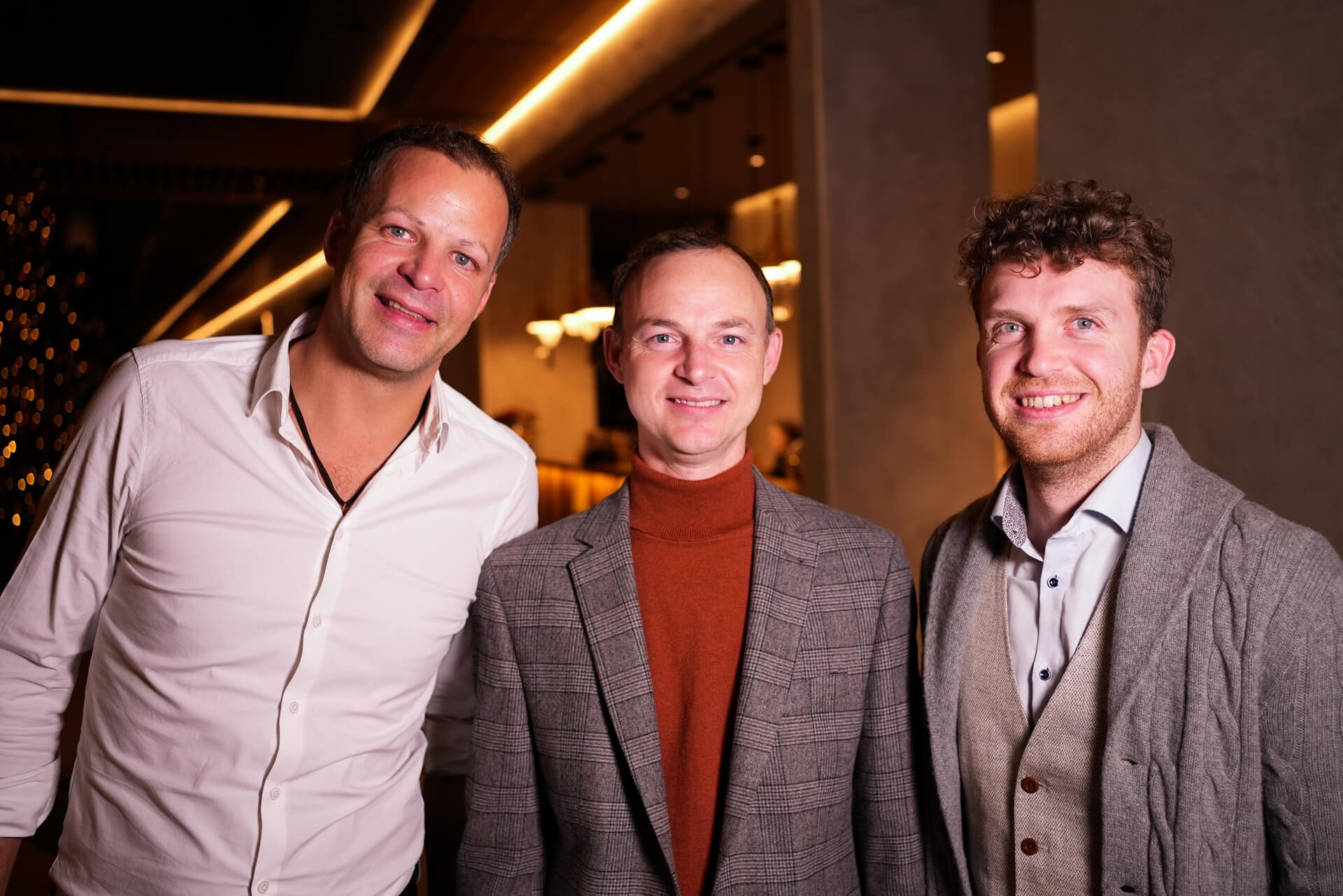 Christoph, Jörg and Gottfried smiling for the photographer at the company's offsite dinner