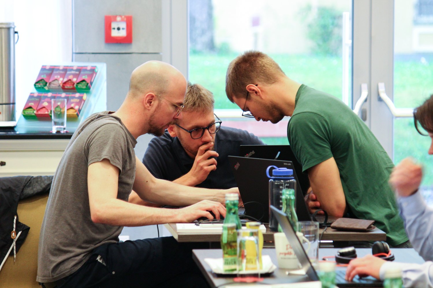 Three hackathon participants looking at their screens together