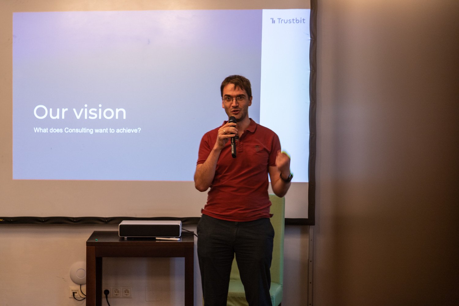 Christian standing in front of a projected slide deck with a microphone, giving a presentation about the Consulting department’s vision at Trustbit