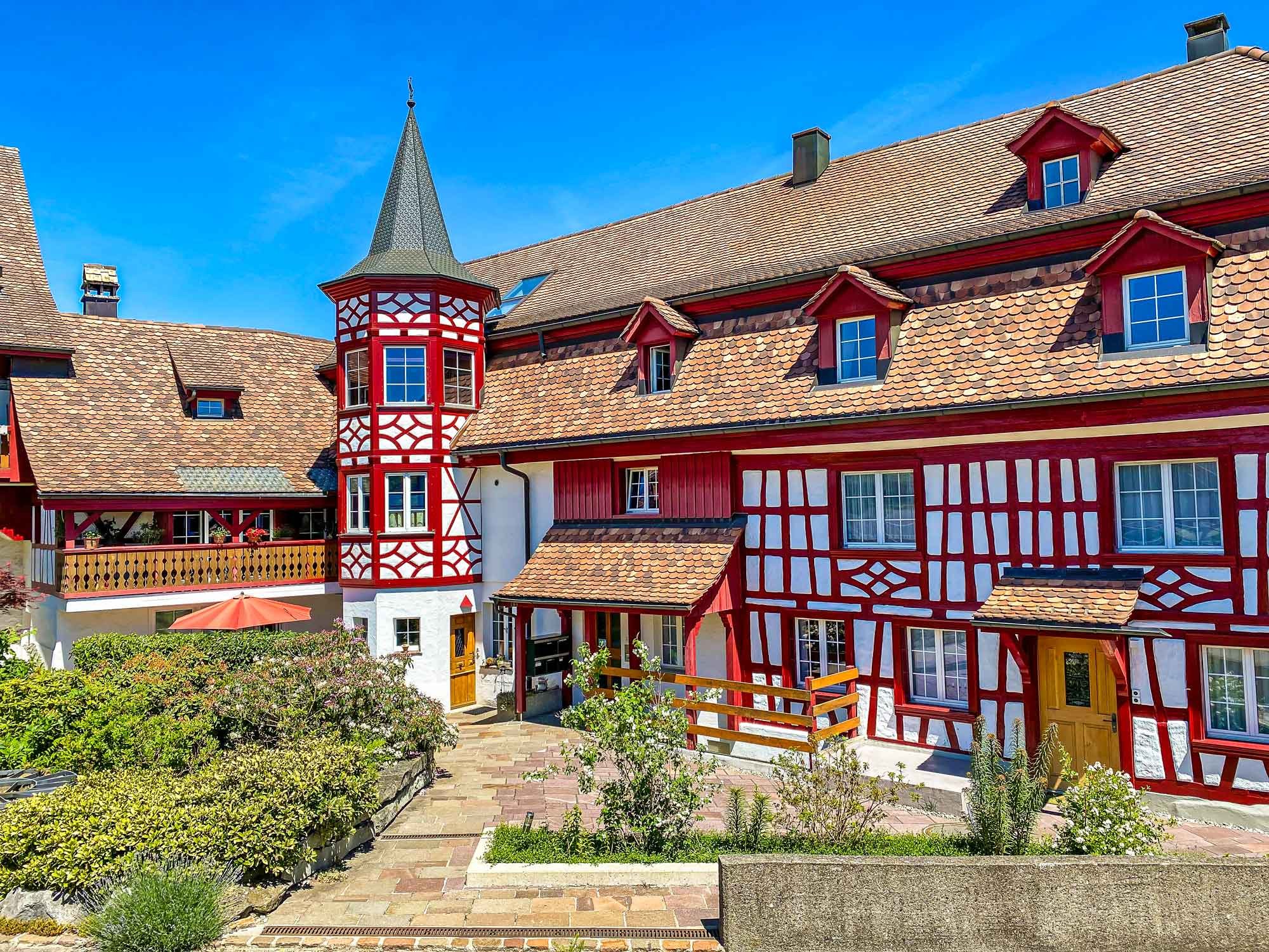 Historisches Gebäude mit Türmchen, roter Riegelbau namens Zehntenhof Design und Fotografie Dan Furrer copyright 2024