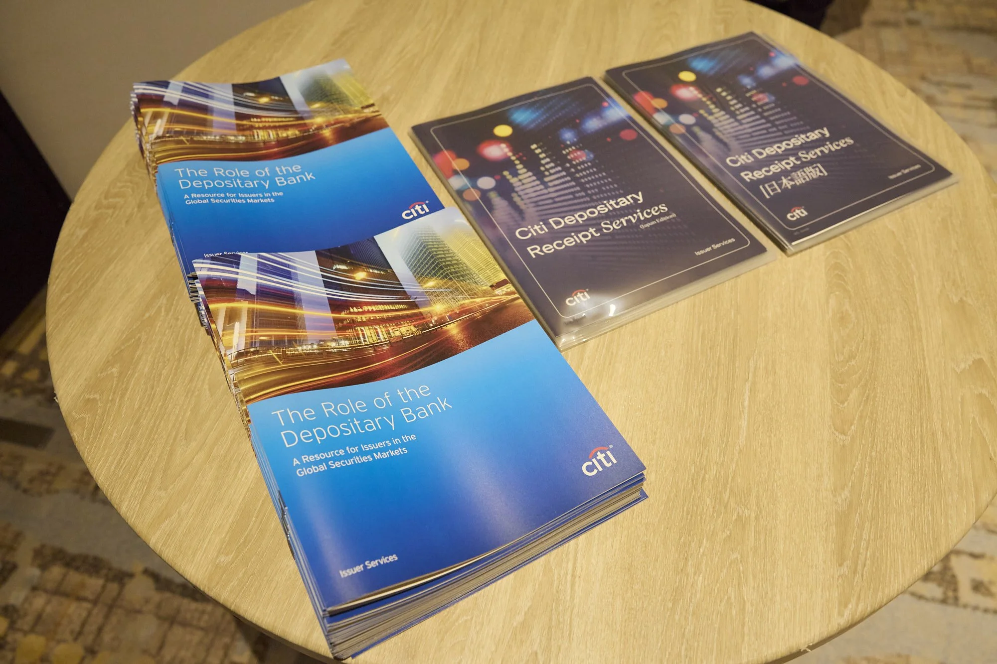 Brochures and booklets about citibank depositary receipt services on a round wooden table.