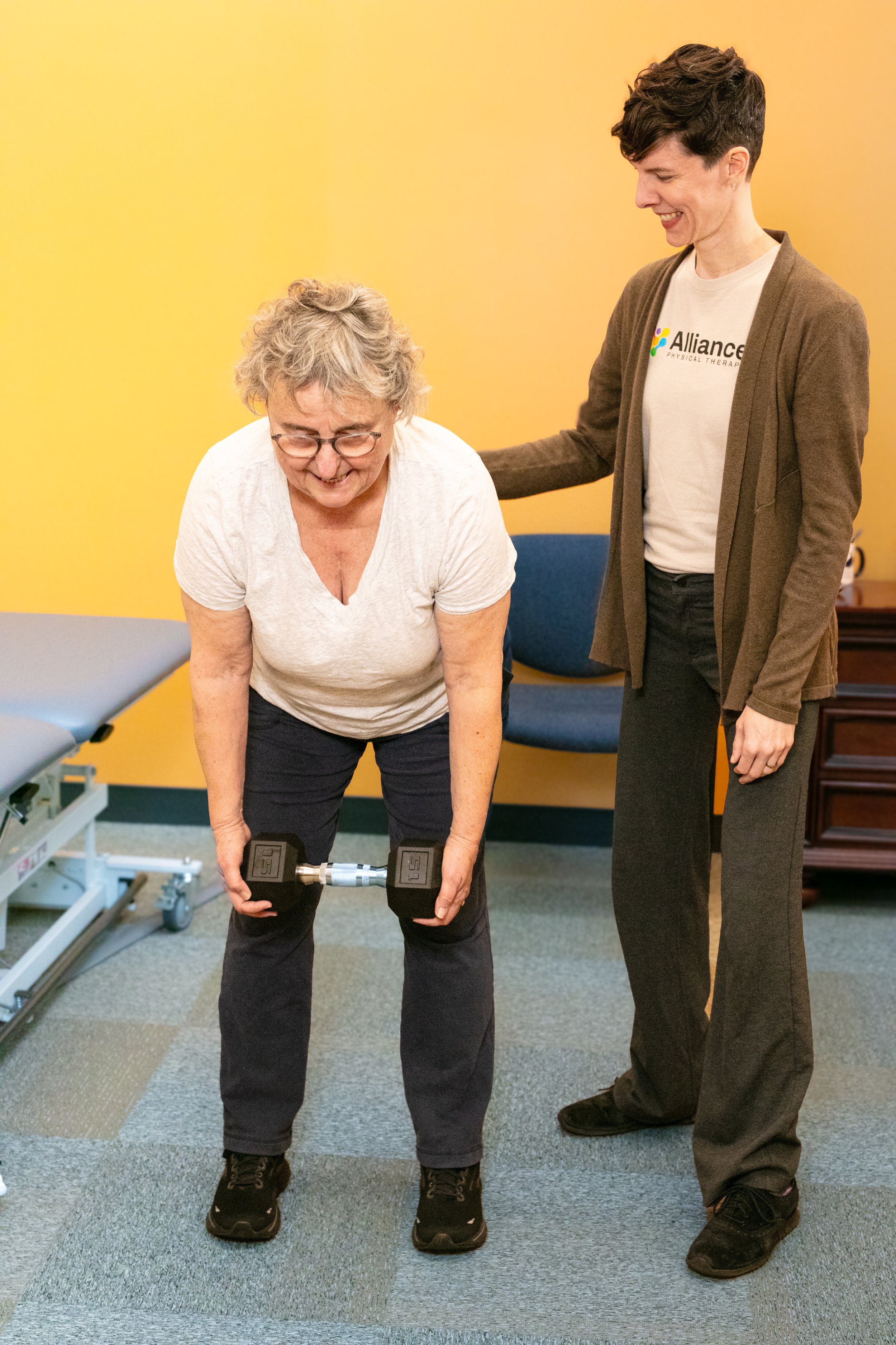 Woman lifting weights with physical therapist support