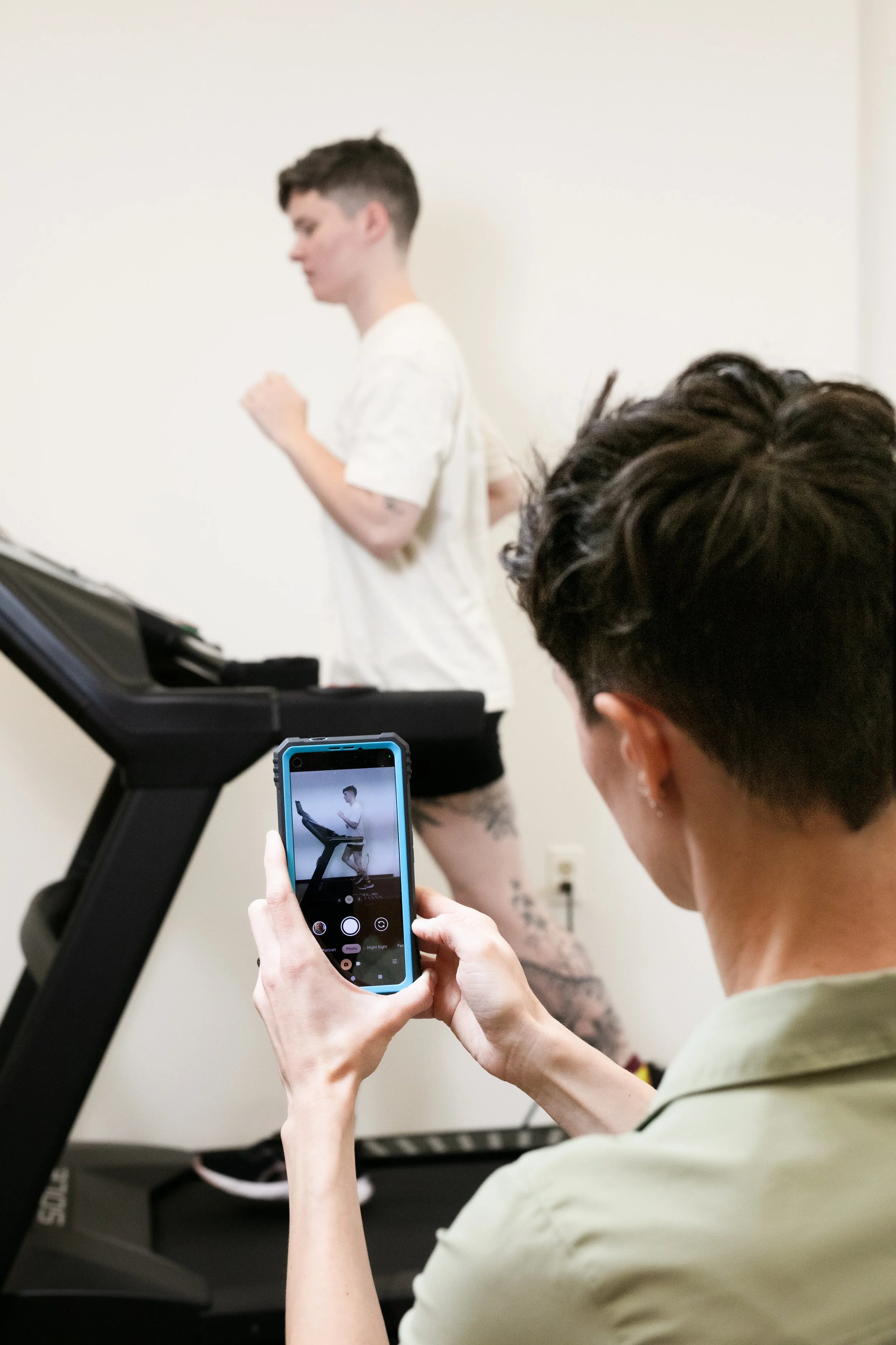 Provider taking video of a patient running on a treadmill
