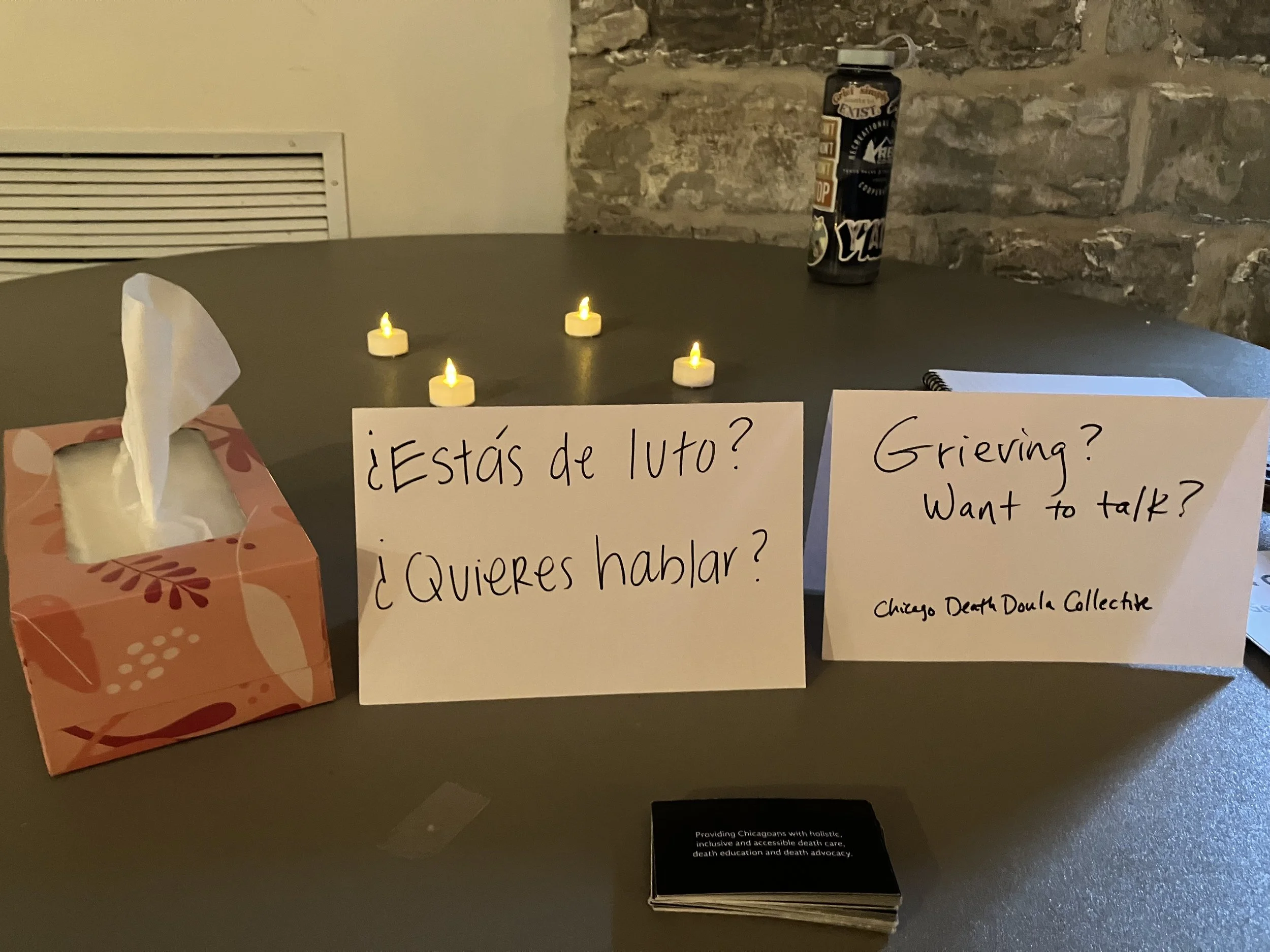 signs on table in Spanish and English reading "grieving? want to talk?"