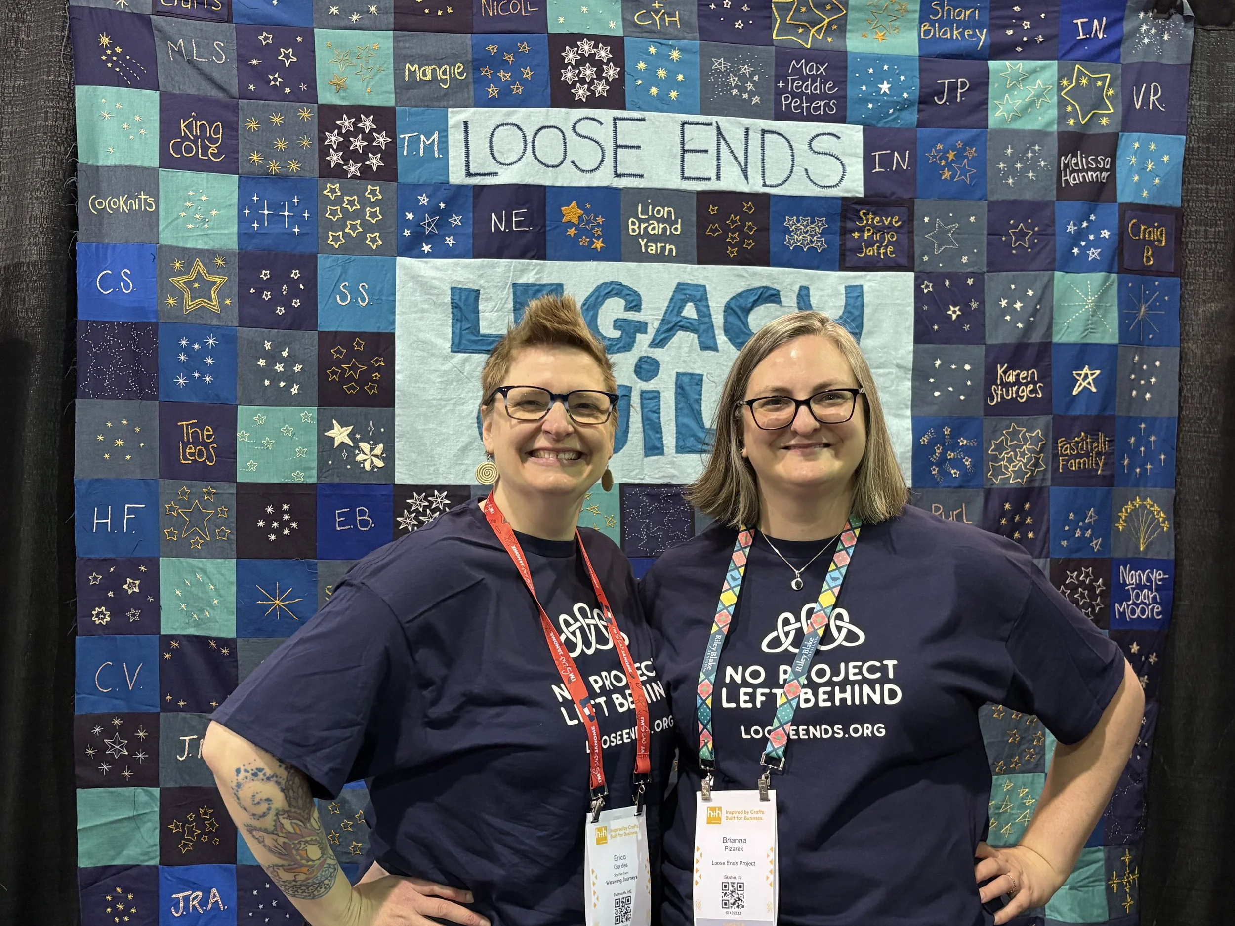 2 people standing in front of a quilt that reads "Loose Ends"