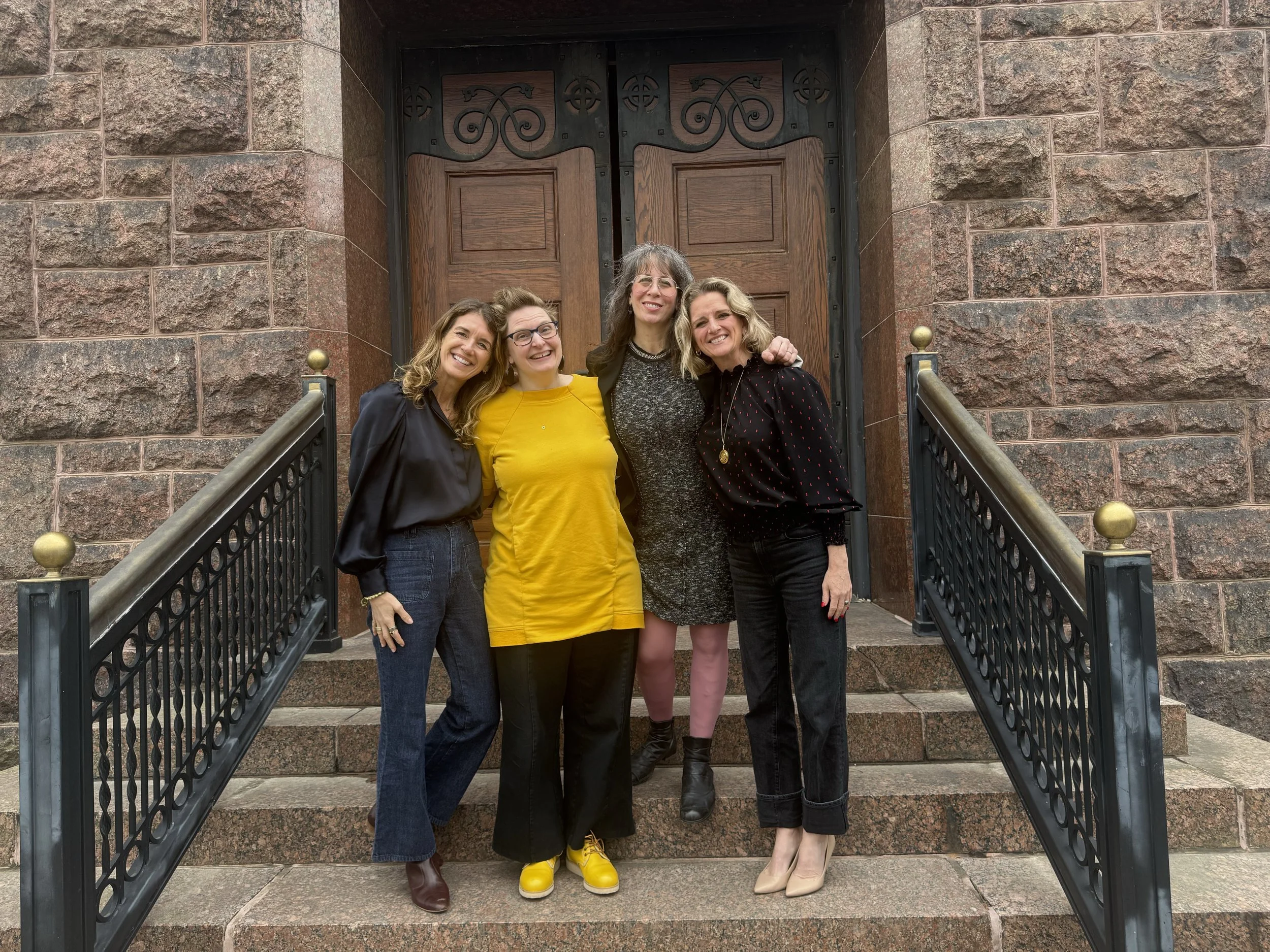 four people posing on steps