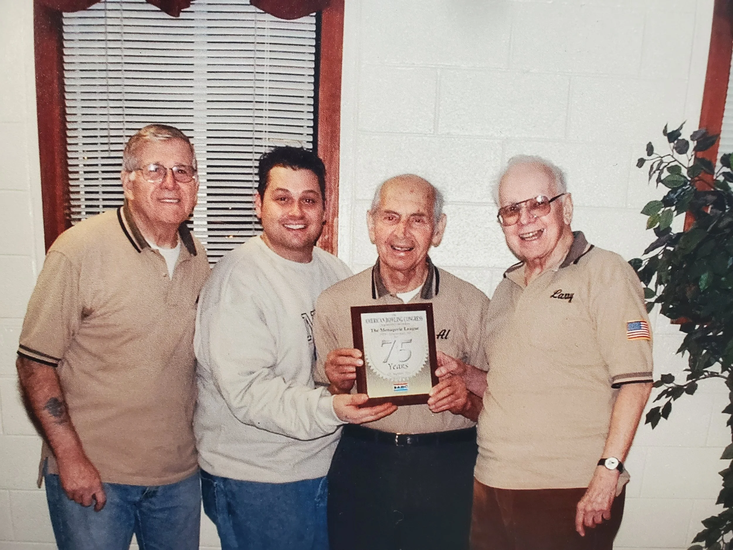 Four men standing with plaque honoring Boulevard Bowl with 75 years in business.
