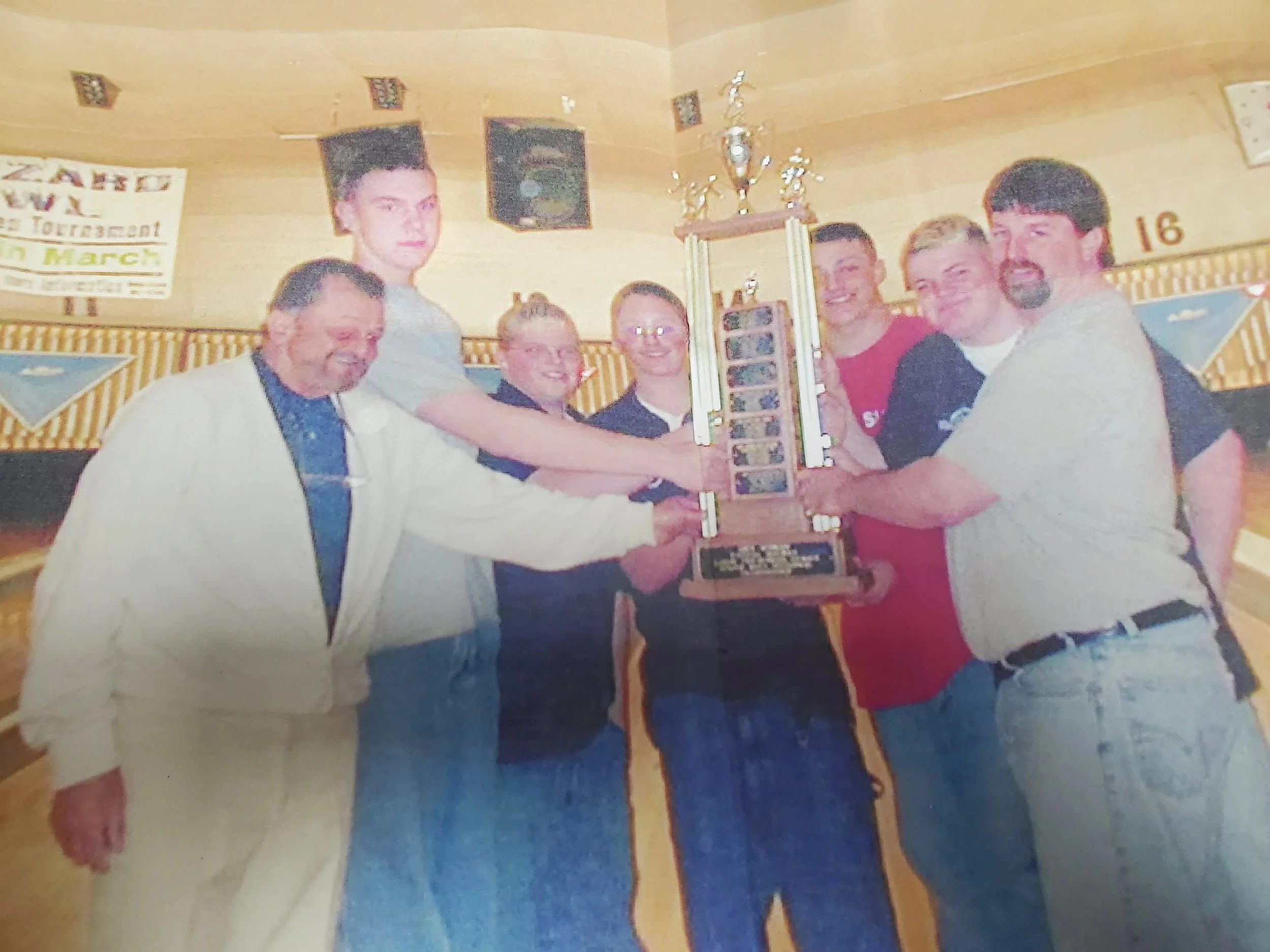 Team of men holding up a trophy for bowling
