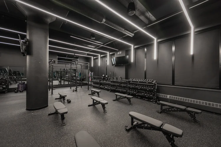 The training floor from the far end, benches and racks along the wall