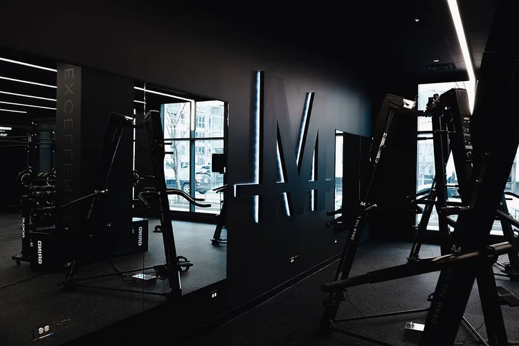 The backlit M mark on the training floor wall, machines either side and the street windows behind