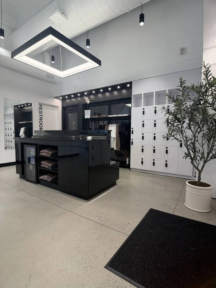 The locker wall and retail rail, a black display island and a potted olive tree