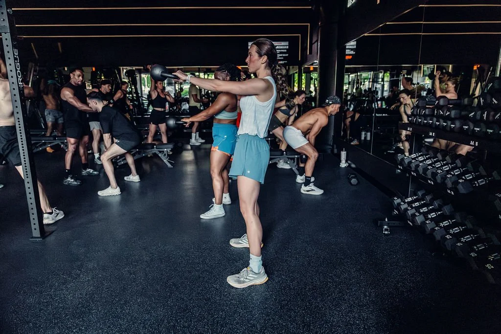 A member swinging a kettlebell mid-session, the class training around them