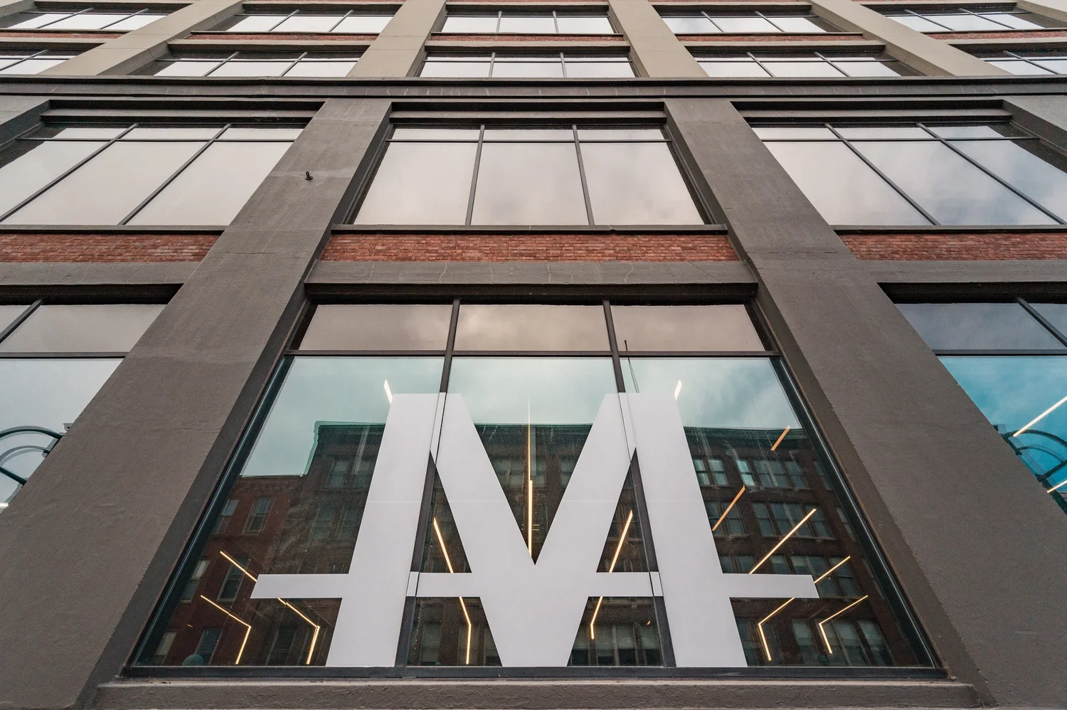 Looking up at the studio building, the TRAIN Moment M mark on the glass facade