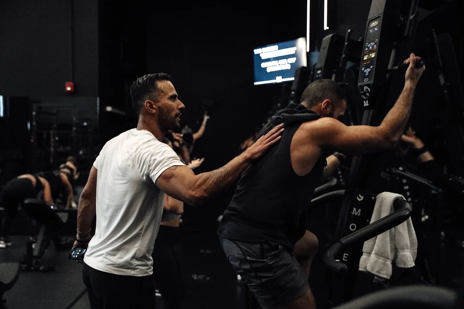 A TRAIN Moment coach with a hand on a client's back, coaching them through a set