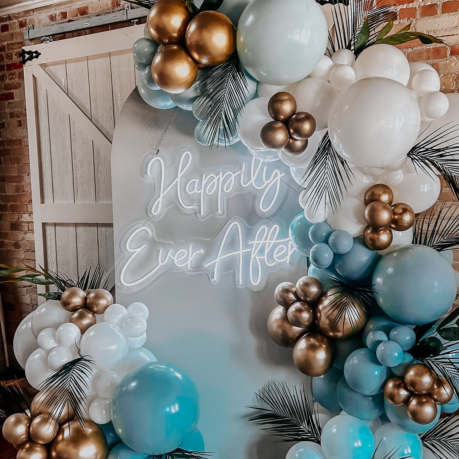 White, mint green, and gold balloon décor with black palm accents framing a “Happily Ever After” neon sign for a 30A engagement party or bridal shower.