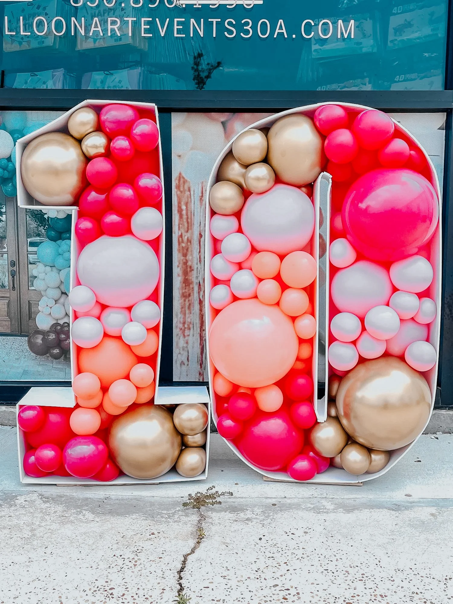 Large “10” marquee frames filled with pink, gold, and peach balloons for a 30A birthday celebration.