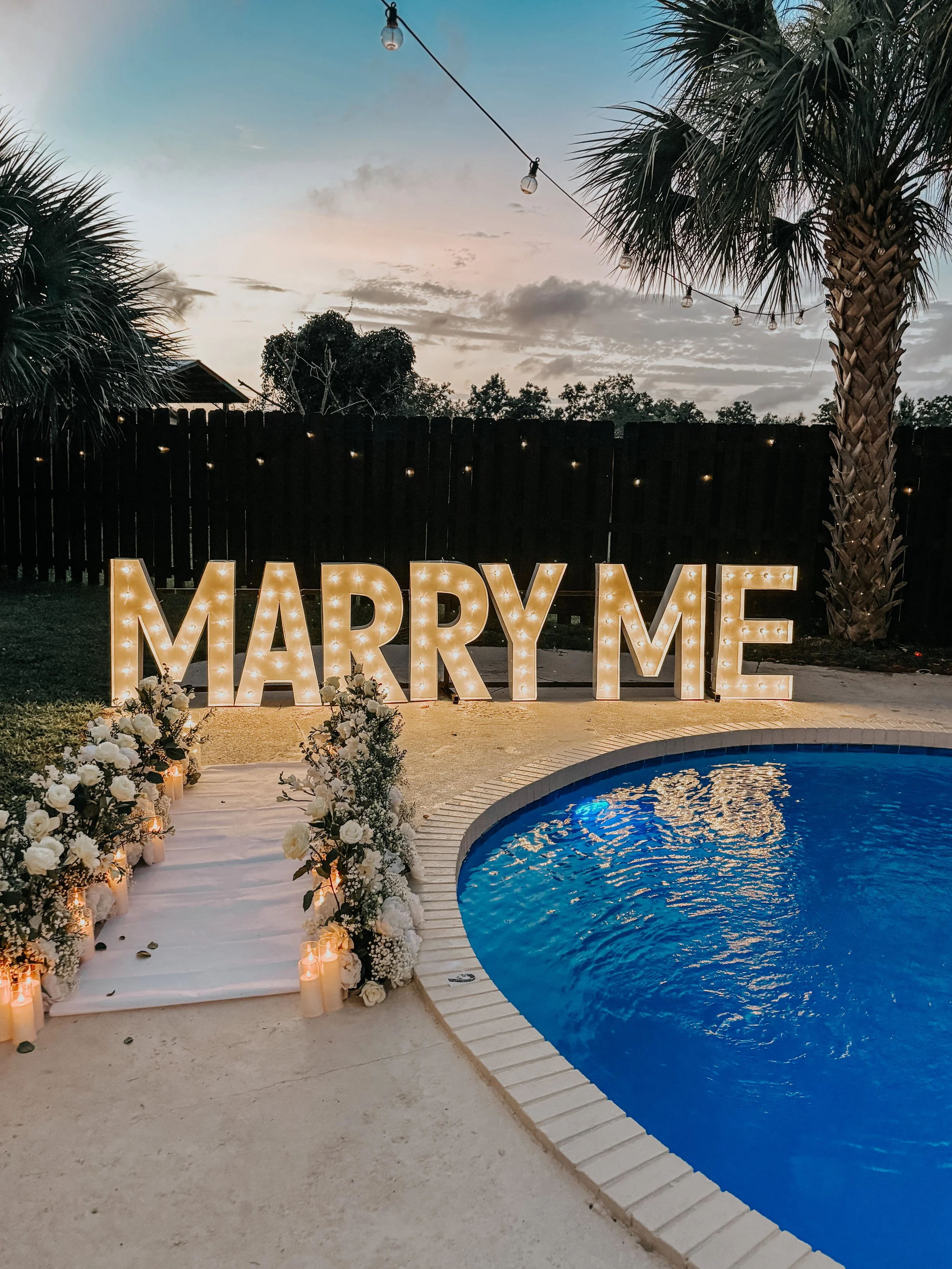 Luxury marriage proposal setup in Alys Beach, Florida featuring illuminated "Marry Me" letters and romantic poolside décor at a private vacation home.