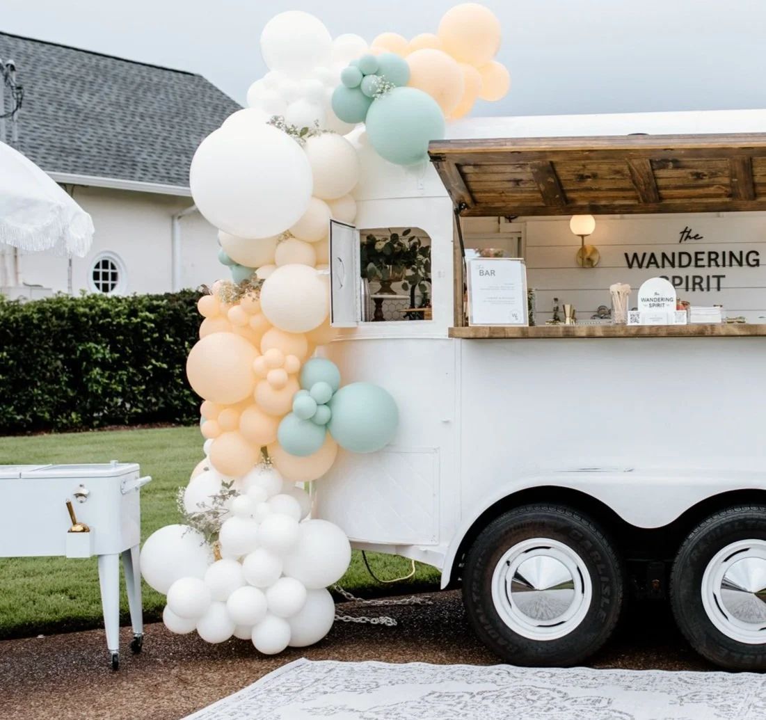 Custom pastel balloon garland decorating a mobile bar at a luxury outdoor event in Alys Beach, Florida. Organic balloon décor for a celebration along Scenic Highway 30A.