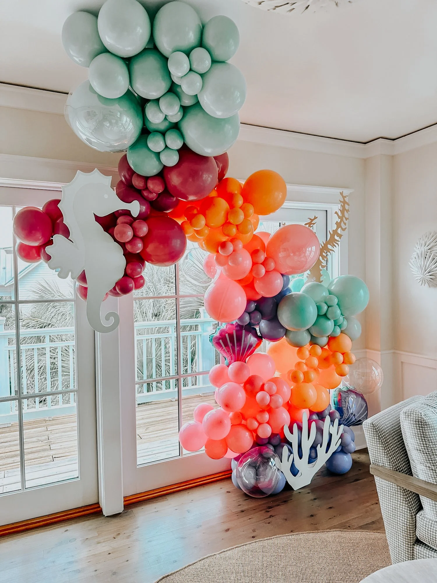 Sea-themed balloon décor with pink, purple, orange, and green balloons plus seahorse and coral accents for a 30A indoor celebration.