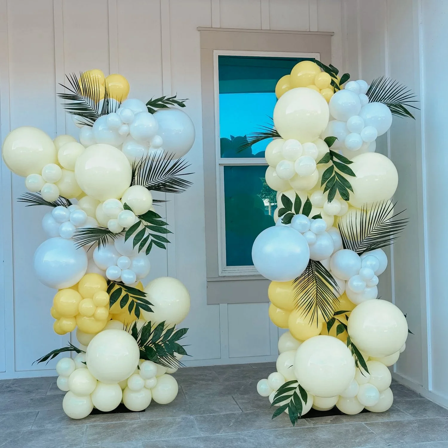 Yellow and white balloon columns with green leaf accents styled for a 30A outdoor celebration.