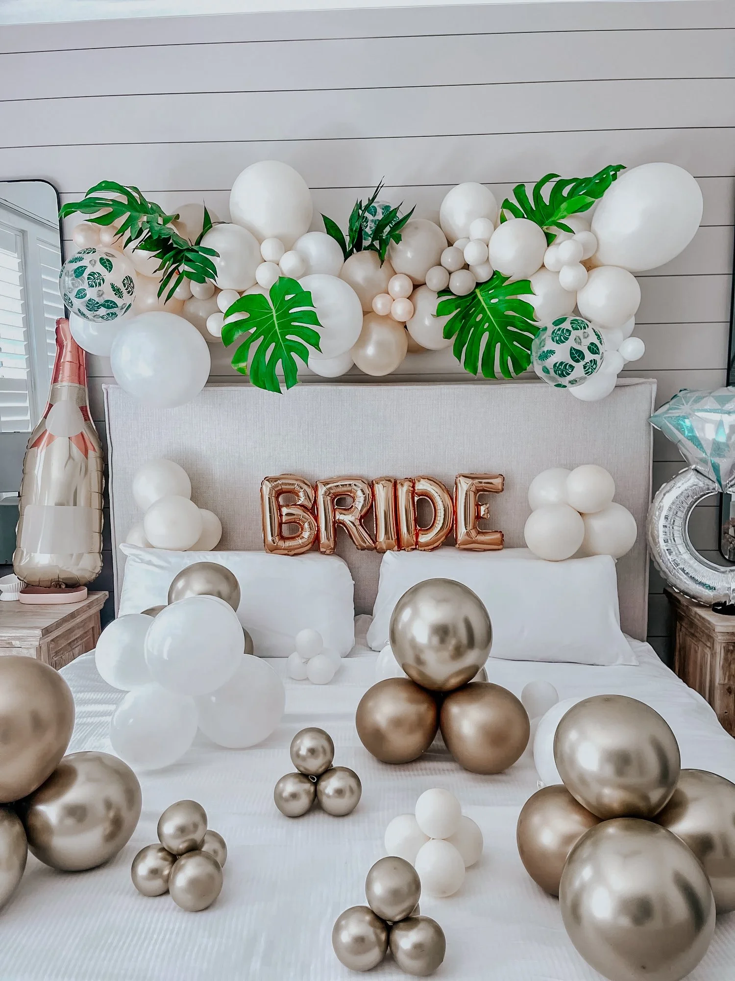 Bridal surprise setup with gold, white, and green balloon garland, helium balloons, floor balloons, and a metallic “BRIDE” banner styled for a 30A bridal shower or bachelorette stay.