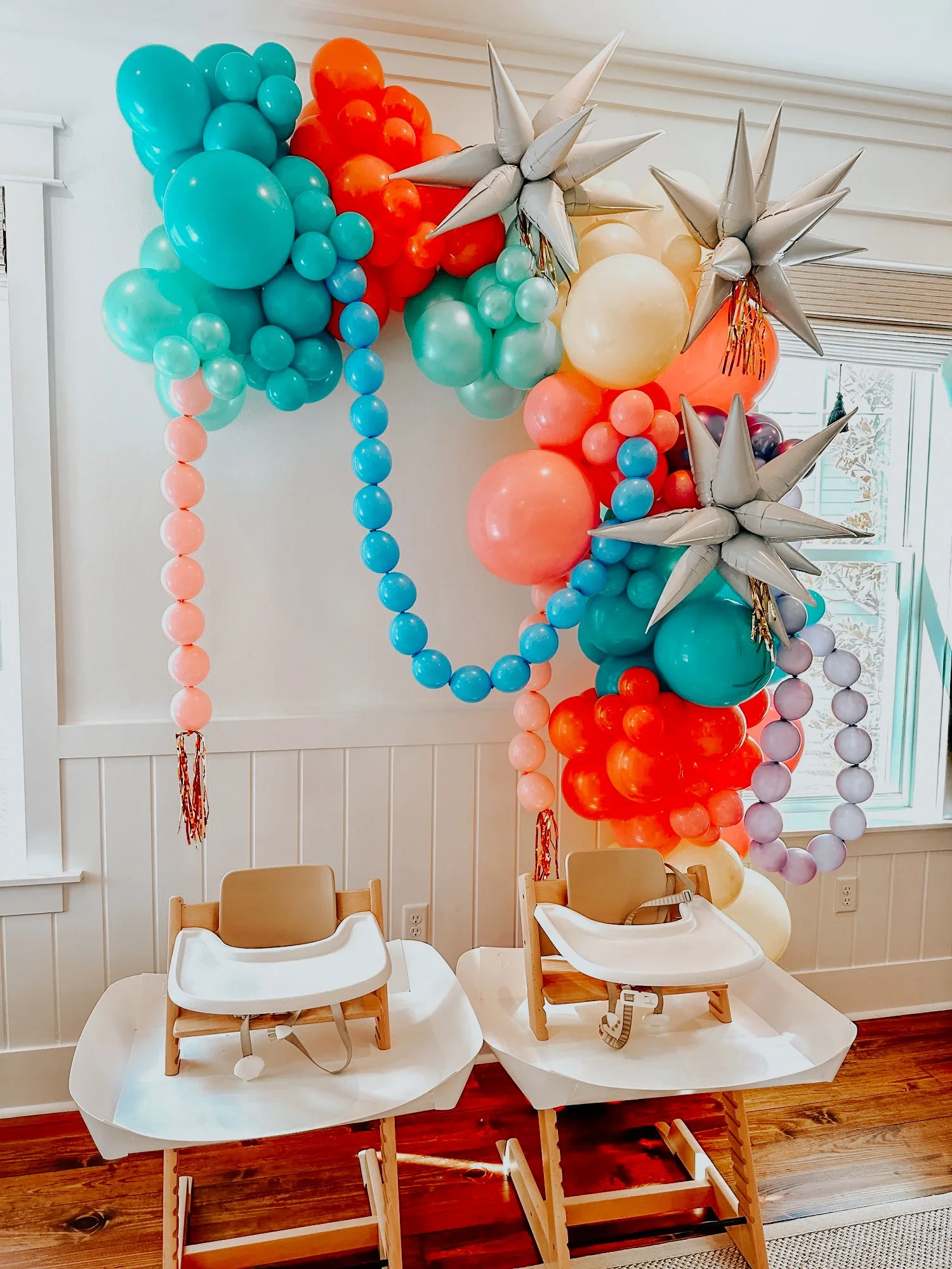 Colorful balloon arch with star accents framing two high chairs for a 30A kids’ celebration or birthday setup.