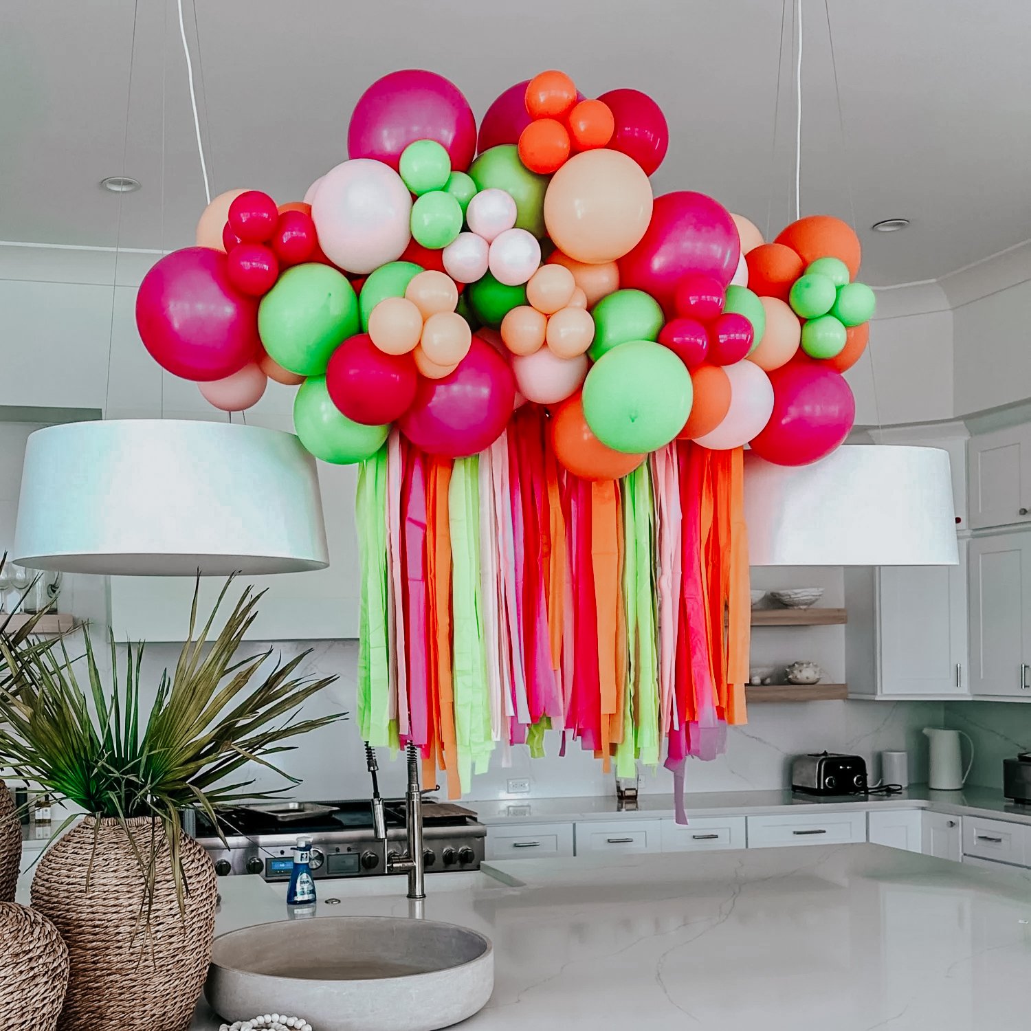 Colorful balloon and streamers on chandelier styled in a modern white kitchen for a 30A vacation rental celebration.