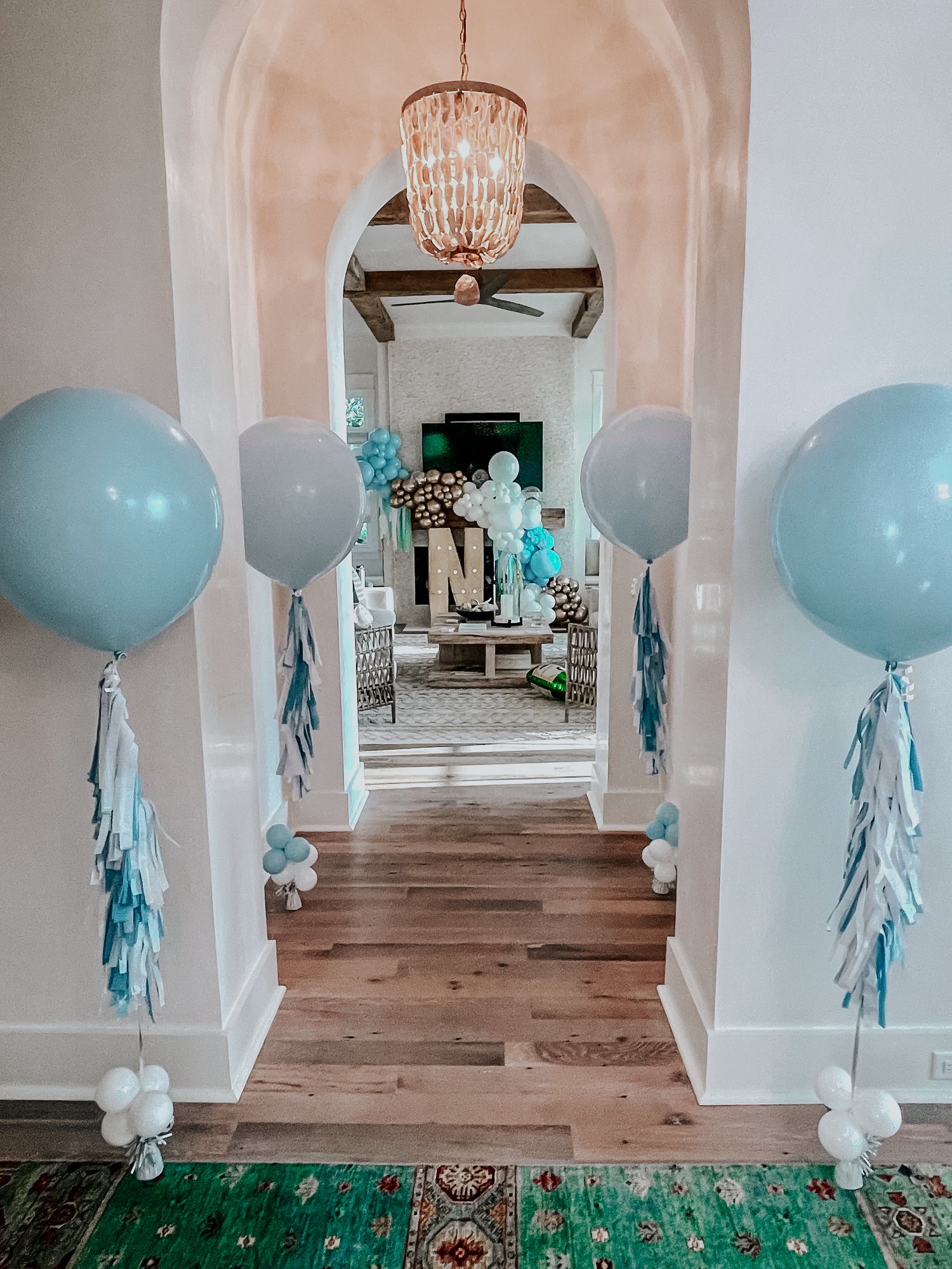 Giant blue and white helium balloons decorating a hallway and living room entrance to welcome guests at a 30A indoor event, like a baby shower.