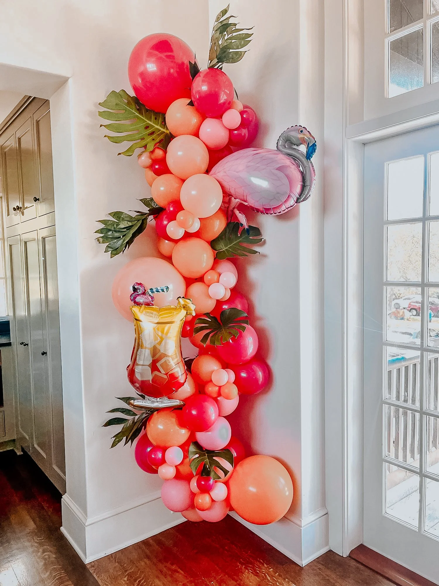 Pink, orange, and purple balloon décor with tropical leaves and flamingo accents for a 30A indoor celebration.